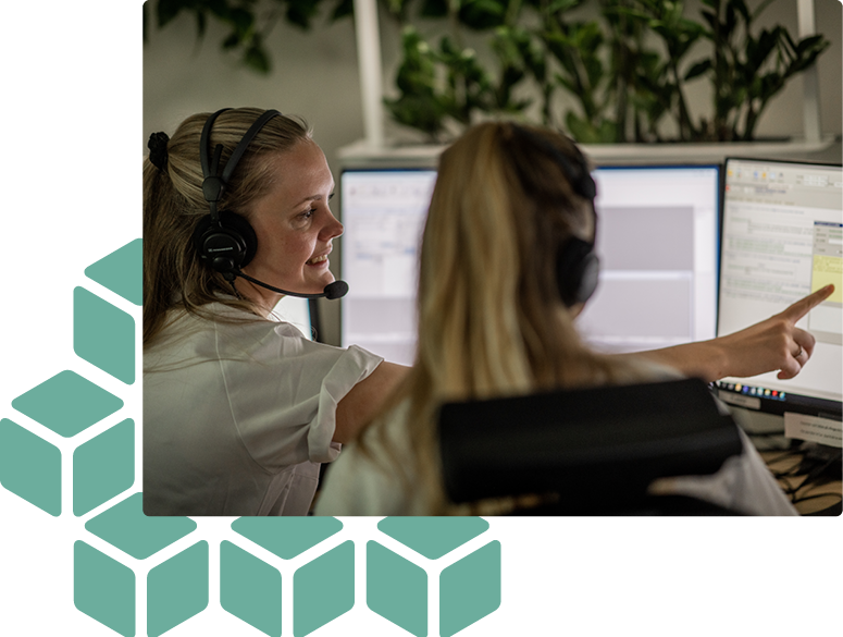 Twee operators zitten bij elkaar en een van hen wijst naar een computerscherm